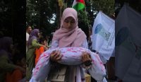 Seorang mahasiswa mengangkat boneka dari kain kafan sebagai simbol banyak anak Palestina jadi korban