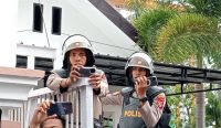Dua aparat kepolisian terlihat merekam momen mahasiswa ricuh saat demo di Kantor DPRD NTB, Rabu, 16 Oktober 2024