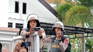 Dua aparat kepolisian terlihat merekam momen mahasiswa ricuh saat demo di Kantor DPRD NTB, Rabu, 16 Oktober 2024