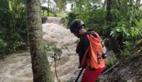 Seorang petugas SAR terlihat mencari remaja yang hilang terseret banjir
